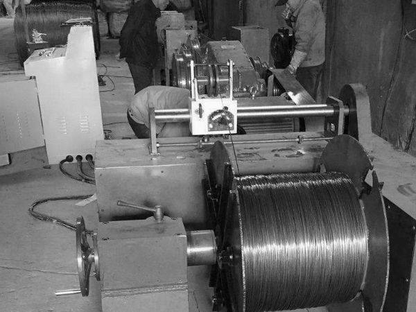 Two workers are operating wire drawing machine.